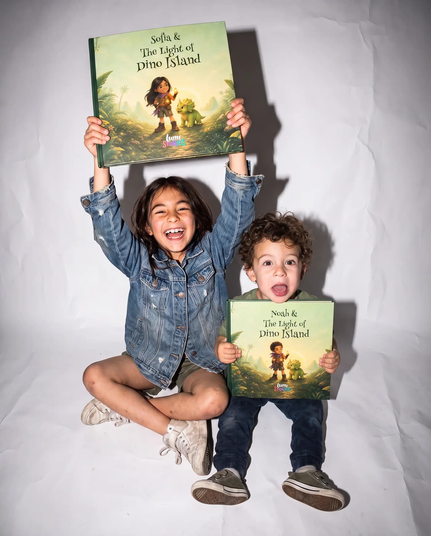 Two siblings on a white studio backdrop, each holding their own copy